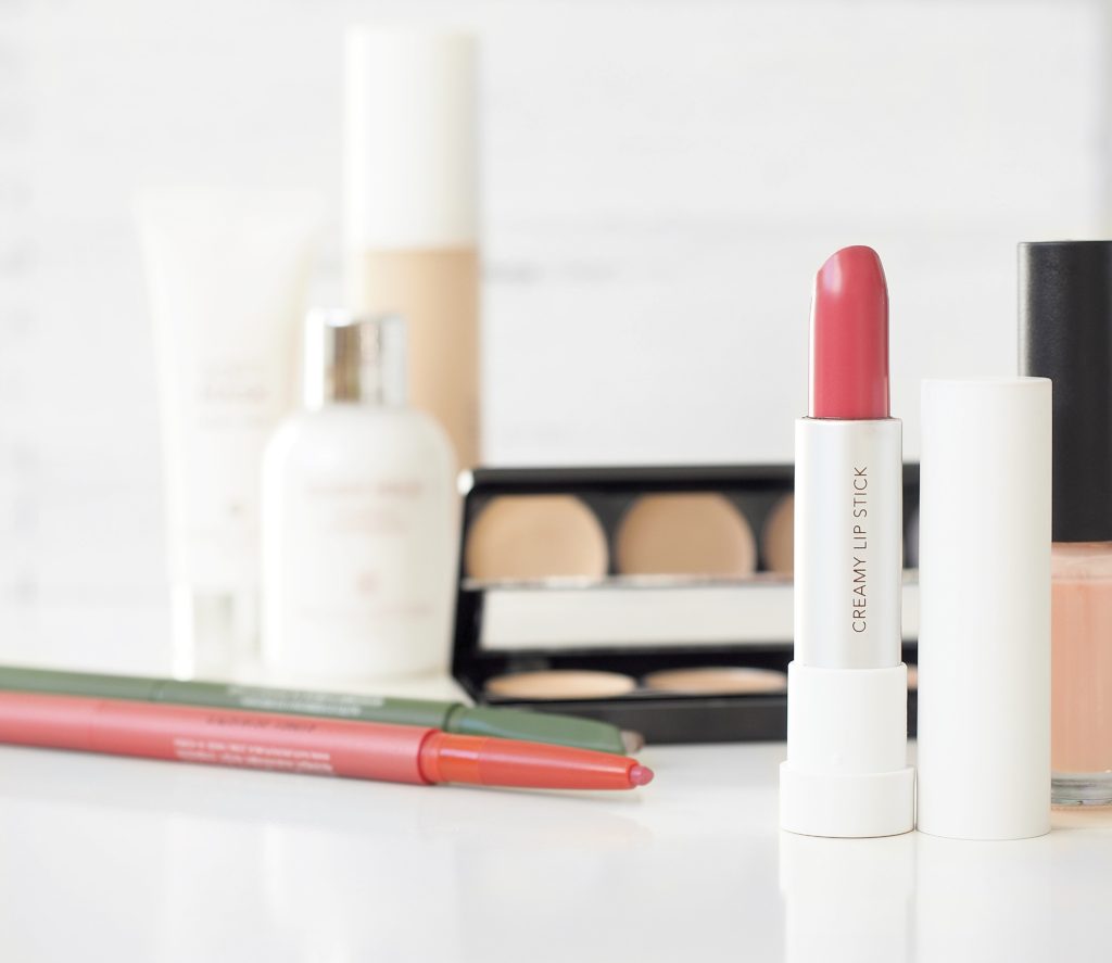 pink lipstick and other makeup products on a white surface